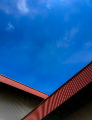 Red roof in a factory with a bright blue sky background.