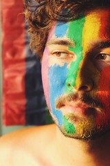 Closeup Portrait of young man face painted as lgbtq rainbow pride flag with sunset sunlight on face and curly hair *4