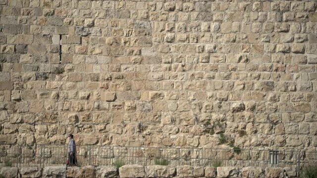 Texture pattern shot of western wall at Jerusalem, Israel. Clean architectural slow motion wide angle shot of people passing by the willing wall. Background bricks panorama concept.