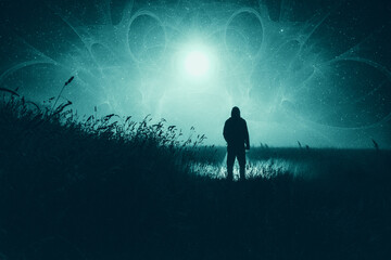 Fototapeta premium A moody science fiction concept, of a figure standing in a field with UFO lights glowing in the sky. On a foggy spooky night.