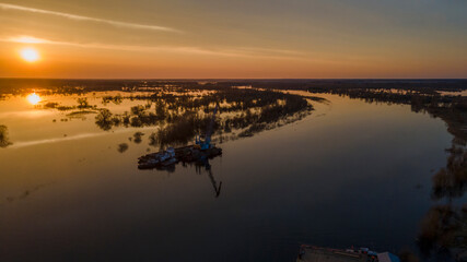 Flooded trees during a period of high water at sunset. Trees in water at dusk. Landscape with spring flooding of Pripyat River near Turov, Belarus. Nature and travel concept.