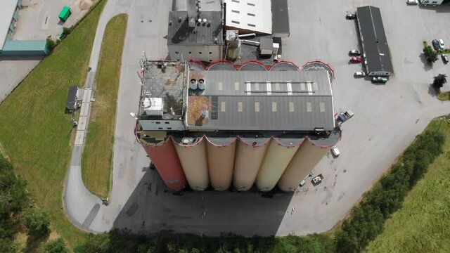 Top down aerial sliding view of Lantmännen Lantbruk industrial crops storage warehouse and large agricultural grains silos located in rural Brålanda town Vänersborg Sweden.
