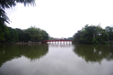 Fototapeta na wymiar Hoan Kiem pool or Lake of the Returned Sword with The Huc red bridge entrance of Ngoc Son temple for vietnamese people and foreign travelers travel visit at Hoan Kiem square city in Hanoi, Vietnam