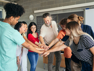 Smiling male teacher celebrating success together with happy multiethnic students. High school, diversity in education