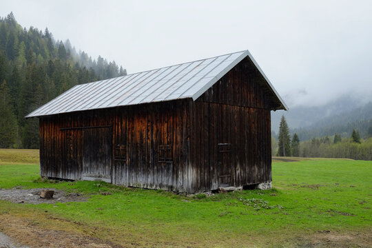 wooden barn on meadow under overcast sky