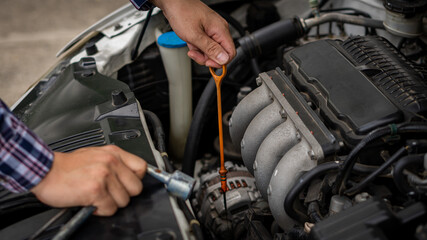 Fototapeta premium A young man checking and maintaining the engine of his car. Open the hood, check the engine safety before long-distance driving,