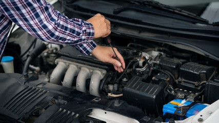Fototapeta na wymiar A young man checking and maintaining the engine of his car. Open the hood, check the engine safety before long-distance driving,