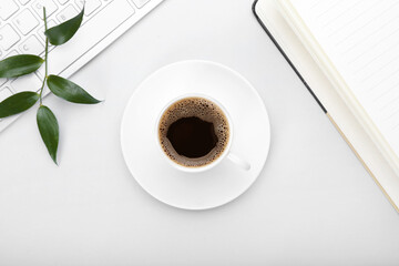Cup of coffee, notebook and keyboard on grey background