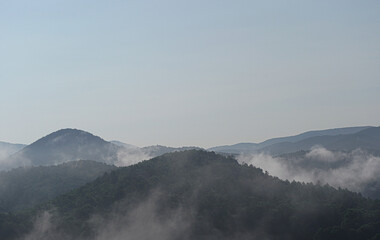 Fog rolls through the picturesque forest mountains.