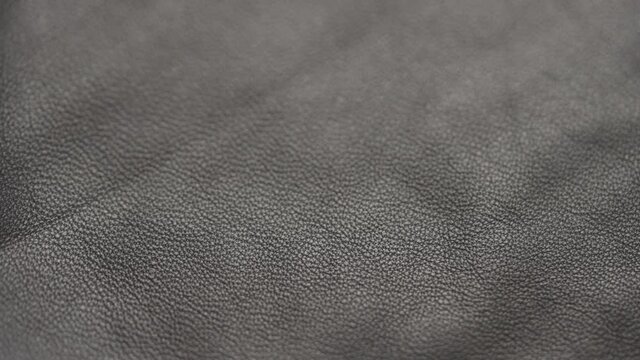 Slow motion handheld shot of soft gray brown leather closeup