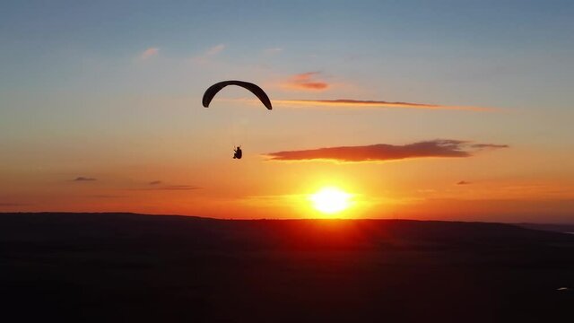silhouette paraglider flying against colorful sunset sky. extreme sports, paragliding. recreational adventure sport.