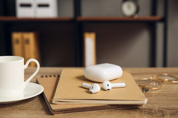 Earphones with notebooks on table in room