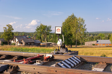 Traffic light on the railway in the village against the background of the forest and blue sky with...