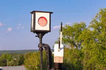 Traffic light on the railway in the village against the background of the forest and blue sky with...