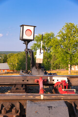 Traffic light on the railway in the village against the background of the forest and blue sky with...