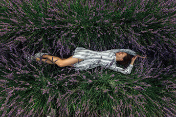 Young woman with lavender bouquet on violet flowers field background