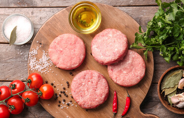 Composition with raw cutlets made of fresh forcemeat on wooden background