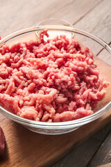 Bowl with fresh forcemeat on wooden background