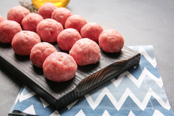 Wooden board with raw cutlets made of fresh forcemeat on dark background, closeup