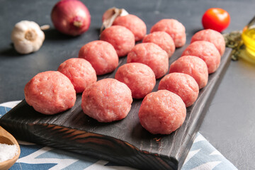 Wooden board with raw cutlets made of fresh forcemeat on dark background, closeup