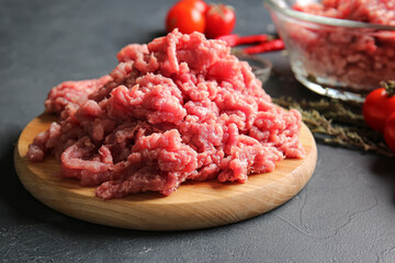 Wooden board with fresh forcemeat on dark background, closeup