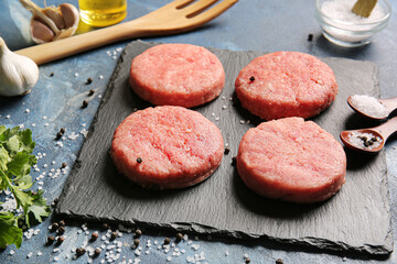 Board with raw cutlets made of fresh forcemeat on color background