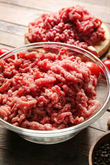 Bowl with fresh forcemeat on wooden background