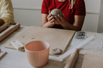 Front view of female potter kneading softly clay on worktop with her hands. - Powered by Adobe