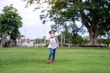 Fototapeta premium Small girl with protective ￼ face mask Running at field￼.
