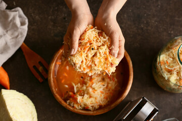 Woman preparing tasty sauerkraut at kitchen table, closeup