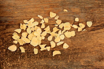 Obraz na płótnie Canvas Dried garlic flakes on old wooden plank background. Dried vegetables