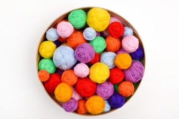 Fototapeta na wymiar A lot of colorful,woolen balls of knitted yarn in a round cardboard box on a white background.The concept of handmade work, needlework and the sale of thread.Top view.Flatlаy.Rainbow layout.Copyspace.