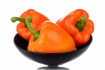 Three organic bell peppers on a ceramic plate, close-up, isolated on white.