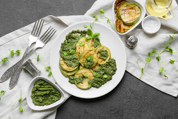 Composition with grilled zucchini, pesto sauce and ingredients on dark background