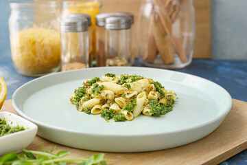 Plate with tasty pasta and sauce pesto on table
