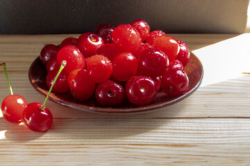 Selected cherry berries. Ceramic saucer, wooden background. Advertising background for dishes with cherries, or freshly frozen cherries