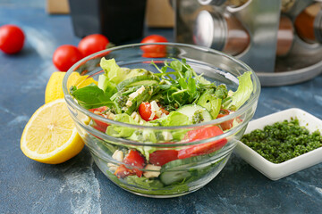 Bowl with tasty salad and pesto sauce on color background
