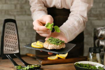 Woman decorating steak with pesto sauce in kitchen