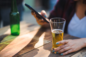 Cropped shot of people holding beer glasses celebrating in the summer camping party outdoor. Friends clinking bottle of beer during camping outdoor