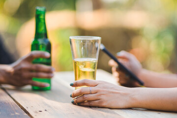 Cropped shot of people holding beer glasses celebrating in the summer camping party outdoor. Friends clinking bottle of beer during camping outdoor