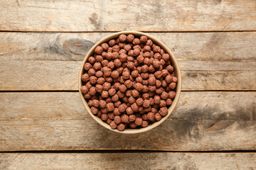 Bowl with chocolate corn balls on wooden background