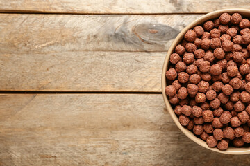 Bowl with chocolate corn balls on wooden background