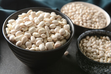Bowls with different types of beans on dark background