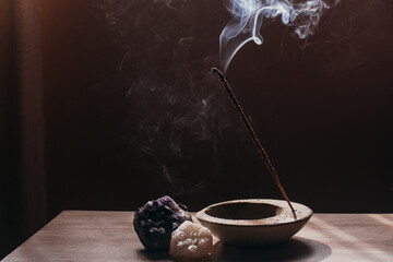 A stick of incense is burned in a room, it emanates aromatic smoke, it is accompanied by crystals.
Aromatherapy, energetic cleansing, relaxation, ritual. - obrazy, fototapety, plakaty