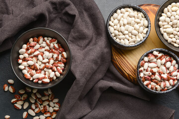 Bowls with raw beans on dark background
