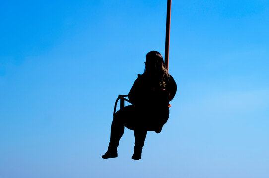 silhouette of woman looking at cell phone in solitary chair lift