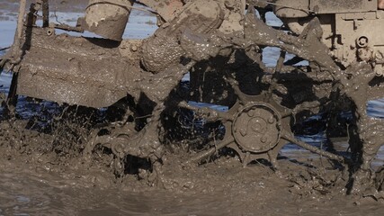 A close up of splashes of mud on a grouser of a tilling machine. A plougher equipment on a farm....