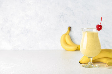 Glass of tasty banana daiquiri cocktail and fruits on table