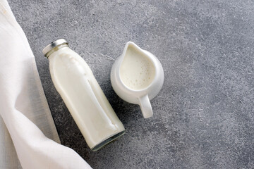 Organic milk in a milk jug  and bottle on a gray concrete background with a white napkin.