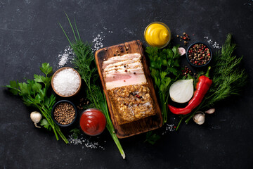 Lard with spices, herbs, mustard and pepper on a wooden board. Ukrainian traditional national cuisine. View from above.